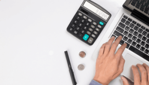 Business photo created by snowing - Calculadora, moedas, caneta e mão mexendo no laptop