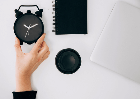 Jornada de trabalho de meio período Pessoa segurando relógio sobre mesa com caderno, café e computador - Imagem de Freepik