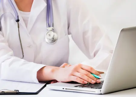 Médica de empresa de prestação de serviços terceirizados mexendo no computador - Imagem de Freepik