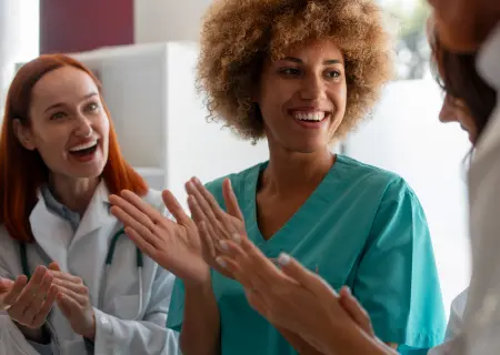 Profissionais de hospital sorrindo e aplaudindo colegas, satisfeitos com sua employee experience - Imagem de Freepik