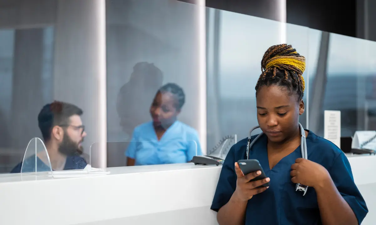 Enfermeira mexendo no celular em aplicativo de plantão enfermagem - Freepik