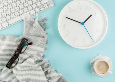 Mesa de trabalho em alusão ao day off, com teclado, relógio, óculos, xícara de café e canga - Imagem de Freepik