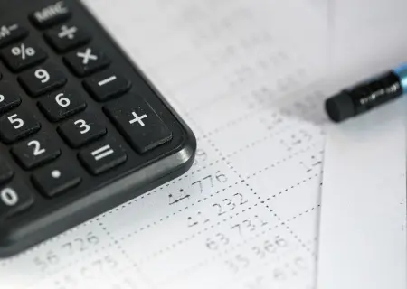 Calculadora e papéis com cálculos mensalista e horista - Imagem de Freepik