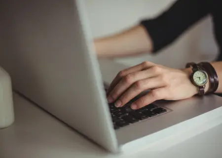 Profissional trabalhando no laptop. Ele possui um relógio no pulso esquerdo - Imagem de Freepik