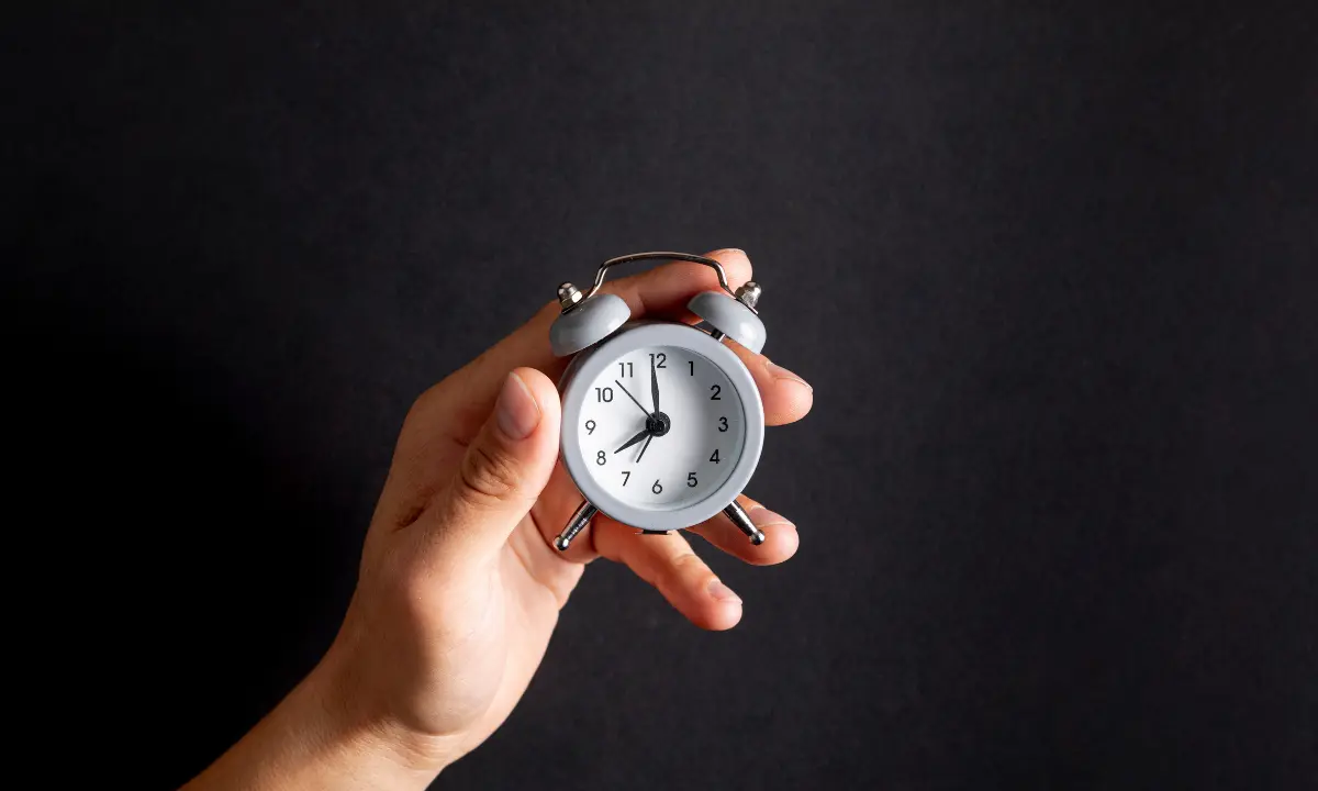 Pessoa segurando relógio indicando realização de hora extra obrigatório - Imagem de Magnific